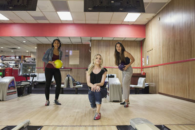 A young women bowling with friends.