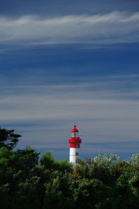 Lighthouse by building against sky