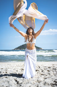 Rear view of woman with arms outstretched standing at beach