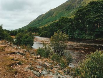 Scenic view of river by mountains against sky