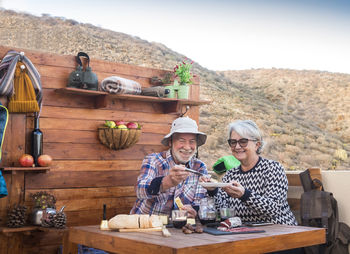 Couple having breakfast while sitting against mountain