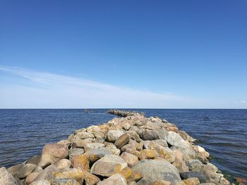 Rocks in sea against blue sky