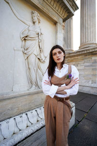 Young woman wearing hat standing against sculpture