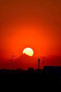 Silhouette built structure against orange sky