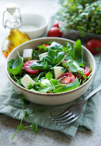 Fresh summer salad with arugula, red cherry tomatoes, basil and mozzarella