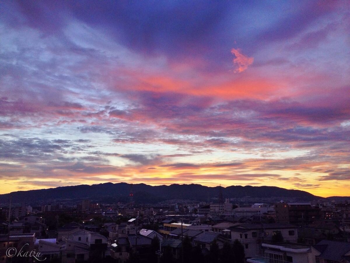 building exterior, architecture, sunset, built structure, sky, mountain, cityscape, cloud - sky, city, residential district, townscape, town, residential building, residential structure, high angle view, orange color, house, mountain range, crowded, cloud