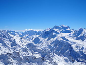 Scenic view of snow covered mountains against blue sky