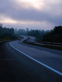 Vehicles on road against sky during sunset