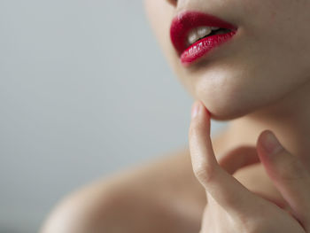 Midsection of topless seductive woman with red lipstick against wall