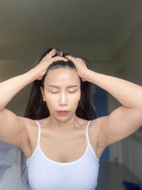 Portrait of young woman looking away against wall