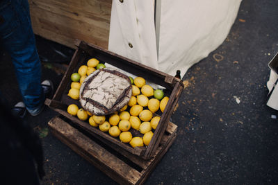 Low section of man standing by crate with lemons