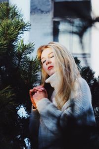 Beautiful young woman wearing hat against trees