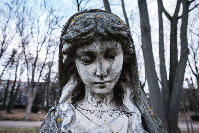 Close-up of female statue against tree trunk