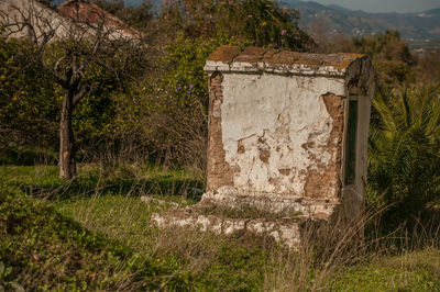 Old house on field against trees