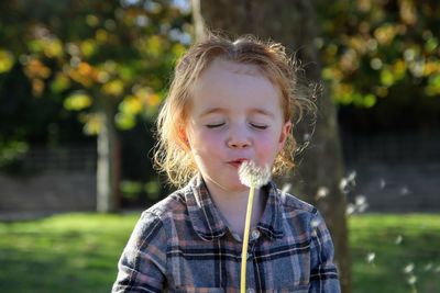 Close-up of girl blowing dandelion at park