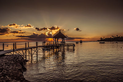 Pier in sea at sunset