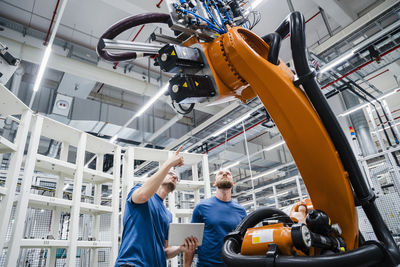 Two technicians examining industrial robot in a factory