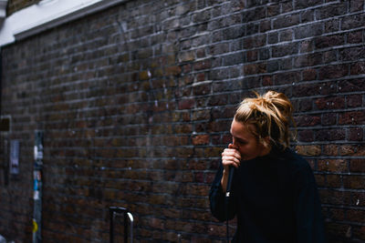 Man standing against brick wall