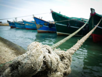 Close-up of fishing boat moored at harbor against sky