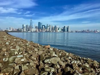 View of city at waterfront against cloudy sky