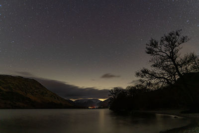 A view of the night sky over ullswater in the english lake district with snow capping the fells
