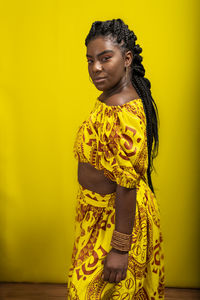 Young woman wearing colorful long clothes over yellow background. isolated yellow background.