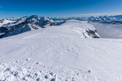 Scenic view of snow covered mountains against blue sky