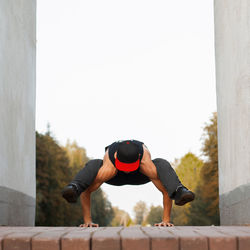 Full length of man photographing while sitting on wall