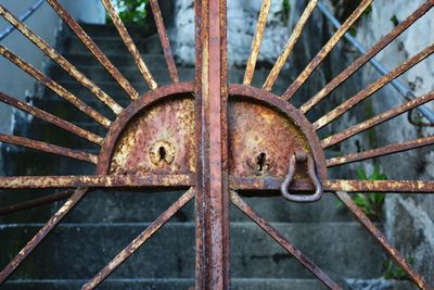 Close-up of closed rusty metal gate by steps