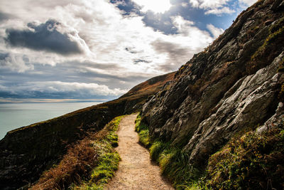 Footpath amidst grass against sky