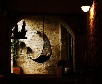 Illuminated lamp hanging on wall in old building