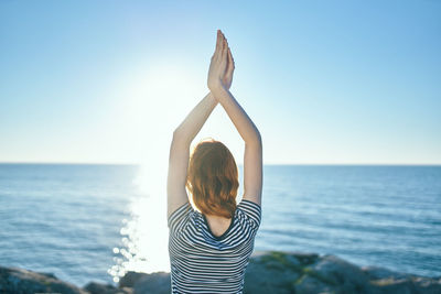 Rear view of woman with umbrella in sea against clear sky