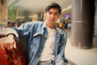 Portrait of good looking asian man sitting in department store 