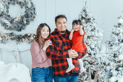 Portrait of smiling family against christmas tree