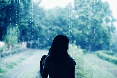 Rear view of woman standing on field during monsoon