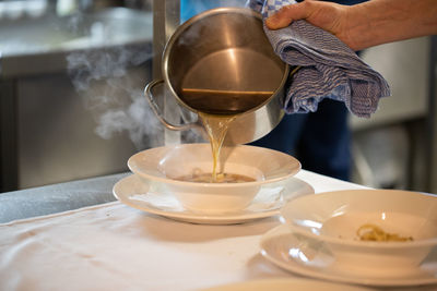 Midsection of person pouring tea in cup