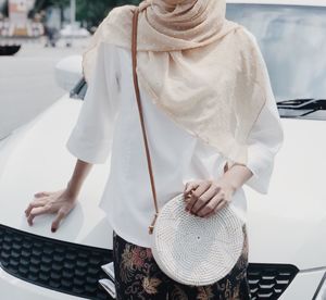 Midsection of woman standing against car on road