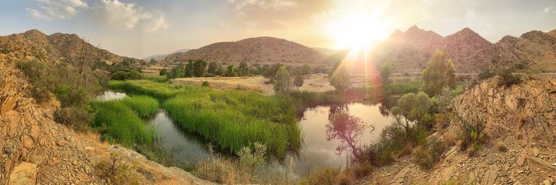 Panoramic view of lake and mountains against bright sun