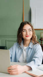 Portrait of smiling young woman using laptop at home