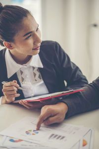 Cropped image of businessman discussing with businesswoman at desk in office