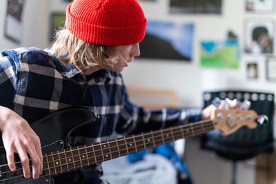 Teenager turning tuning keys on head of bass guitar white tuning