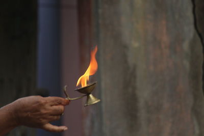 Cropped hand of man holding burning diya during religious ceremony
