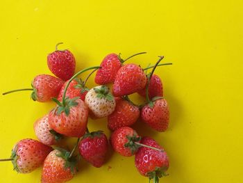 High angle view of strawberries on table against yellow background