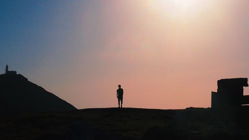 Silhouette man standing on street against sky during sunset