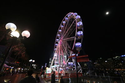 Low angle view of illuminated ferris wheel against sky at night