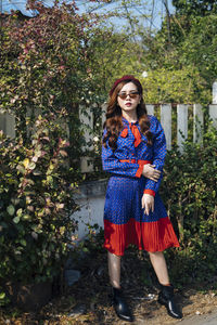 Full length of young woman standing against plants