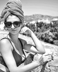 Portrait of young woman wearing sunglasses while sitting at beach