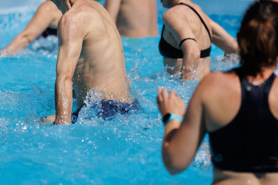 People doing water aerobics outdoor in a swimming pool.