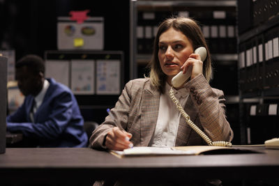 Portrait of young woman using mobile phone in office