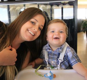 Portrait of smiling mother with cute son sitting on high chair